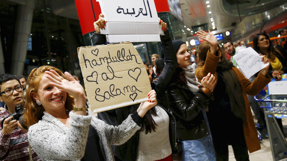 Wellwishers applaud and hold up signs welcoming migrants as Syrian families disembark a train that departed from Budapest's Keleti station at the railway station of the airport in Frankfurt, Germany, early morning September 6, 2015. Austria and Germany threw open their borders to thousands of exhausted migrants on Saturday, bussed to the Hungarian border by a right-wing government that had tried to stop them but was overwhelmed by the sheer numbers reaching Europe's frontiers. REUTERS/Kai Pfaffenbach - RTX1RABZ